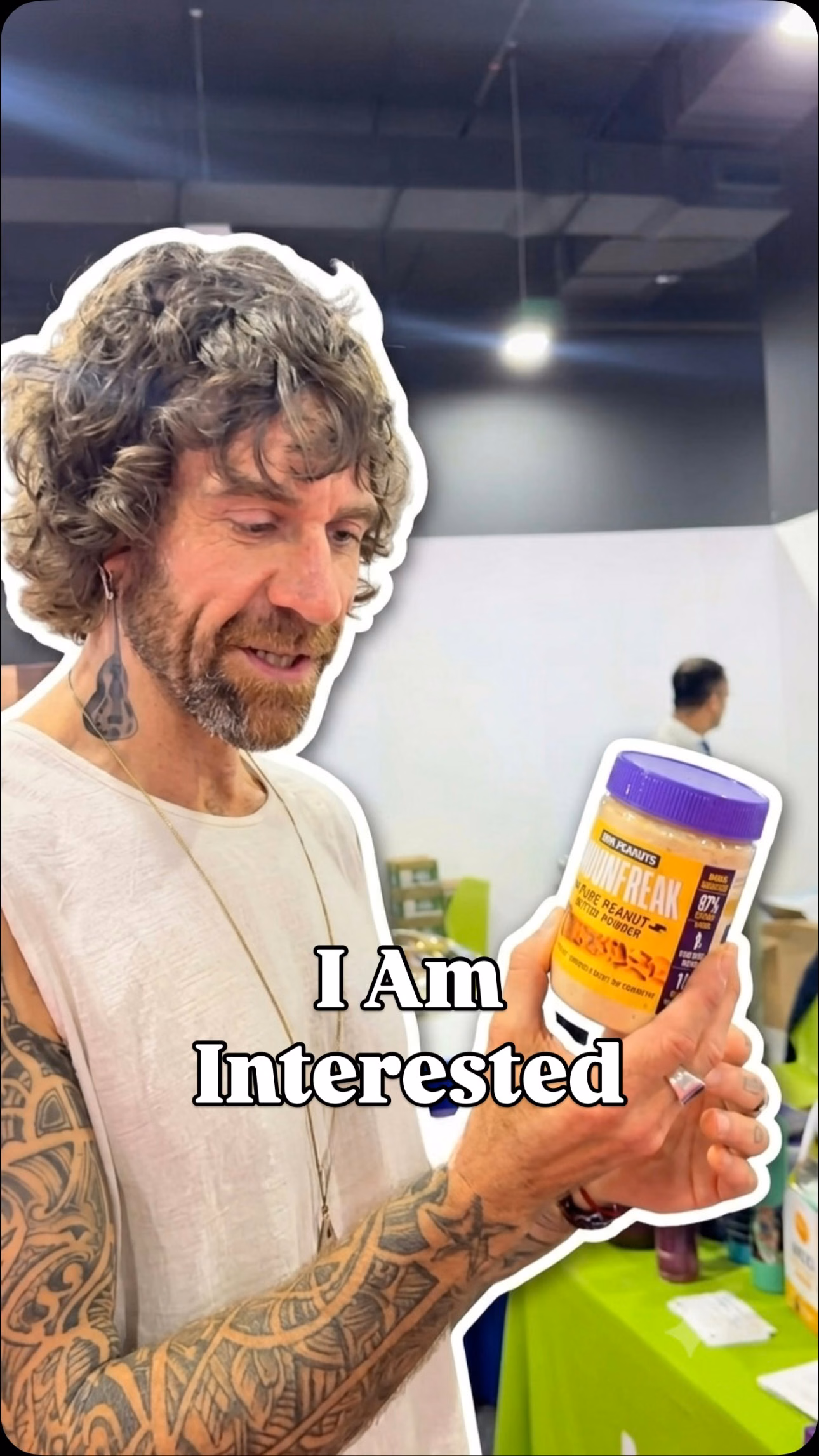 Man holding a jar of Mornfreak Pure Peanut Butter Powder with the overlay I Am Interested